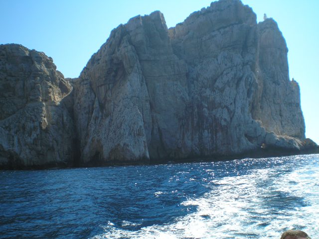 Le alte roccie svettano intorno alla nave, specchiandosi in un mare azzurrissimo, cristallino, solcato solo dalla scia della nave.